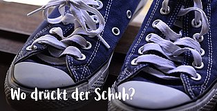 Ein paar Turnschuhe - und darüber der Schriftzug "Wo drückt der Schuh?"